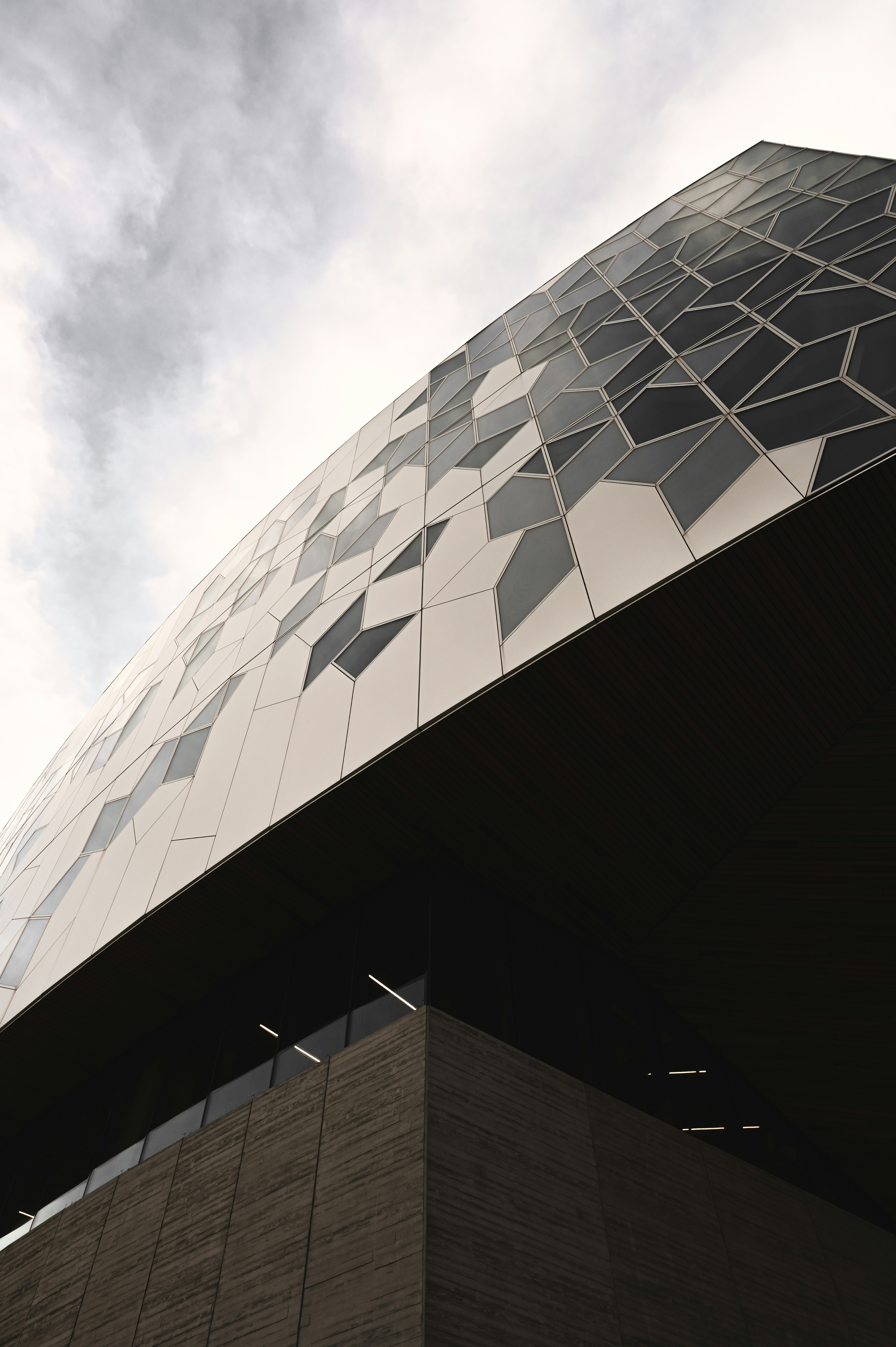 low angle photography of gray concrete building under white clouds during daytime